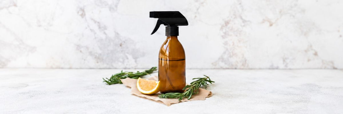 mber glass spray bottle of DIY cleaner with lemon