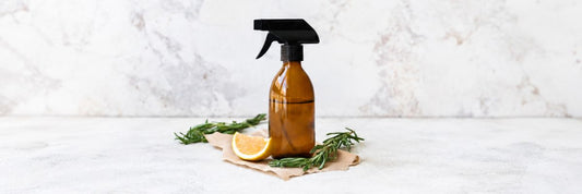 mber glass spray bottle of DIY cleaner with lemon
